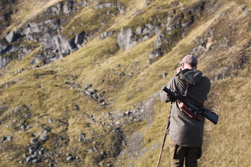 Person with binoculars in hillside landscape.
