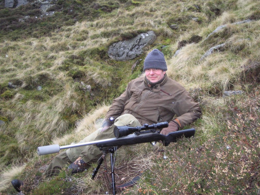Person with rifle resting on hillside