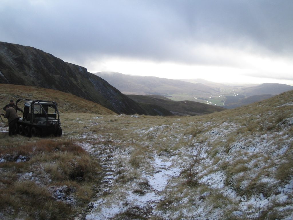 Snowy hillside with vehicle and distant valley view.